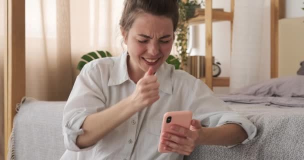 Беспокойная женщина празднует успех онлайн с помощью мобильного телефона — стоковое видео