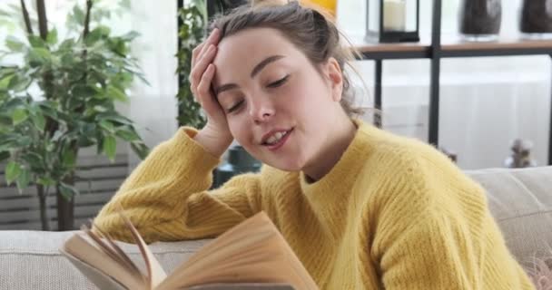 Frau liest zu Hause ein Buch auf Sofa — Stockvideo