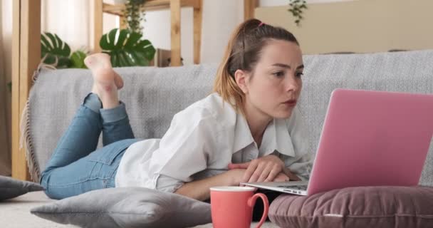 Frau benutzt Laptop, der zu Hause auf Teppich liegt — Stockvideo