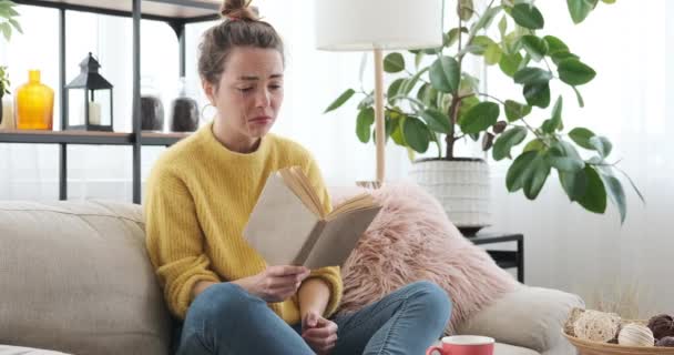 Mulher sensível chorando enquanto lê livro em casa — Vídeo de Stock