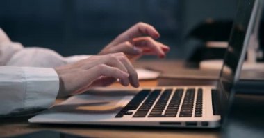 Gece ofisinde dizüstü bilgisayar kullanan bir iş kadını.