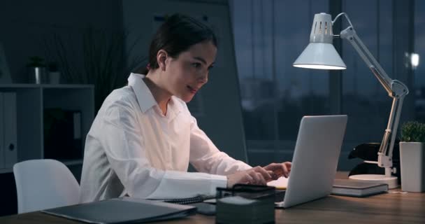 Бизнесвумен празднует успех онлайн в ночном офисе — стоковое видео