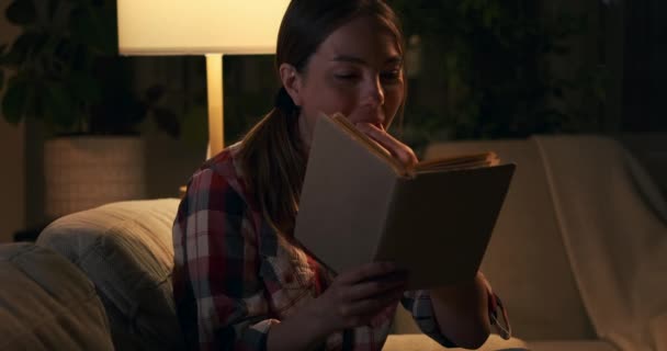 Vrouw die 's nachts popcorn eet en boek leest — Stockvideo
