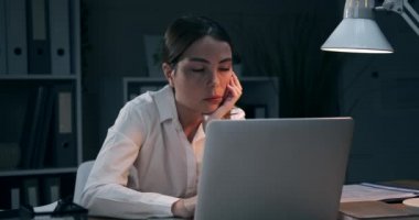 Gece ofisinde gerinen çok çalışan bir iş kadını.
