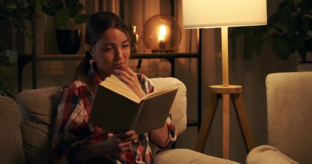 Mujer sensible llorando mientras lee libro por la noche — Vídeo de stock