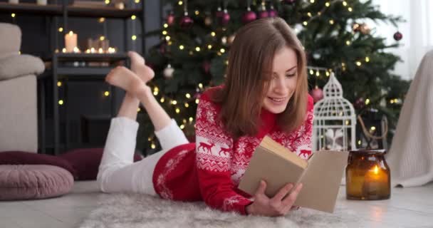 Femme lisant un livre à côté de l'arbre de Noël à la maison — Video