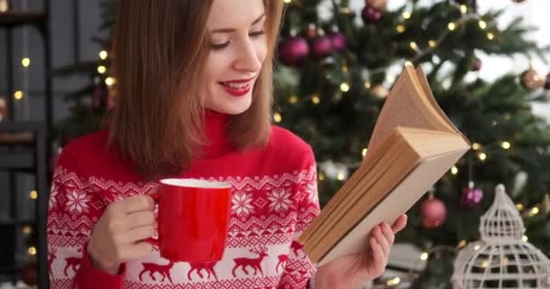 Жінка п'є каву і читає книгу вдома — стокове відео