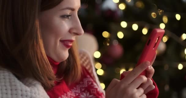 クリスマスの間に携帯電話を使って楽しんでいる女性 — ストック動画