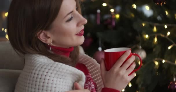 クリスマスツリーでコーヒーを飲む女性を喜ばせます — ストック動画