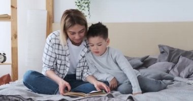 Anne ve oğlu yatakta kitap okuyorlar.