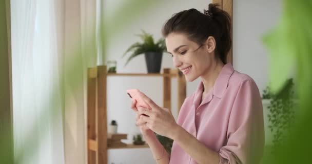 Mujer feliz usando el teléfono móvil en casa — Vídeos de Stock