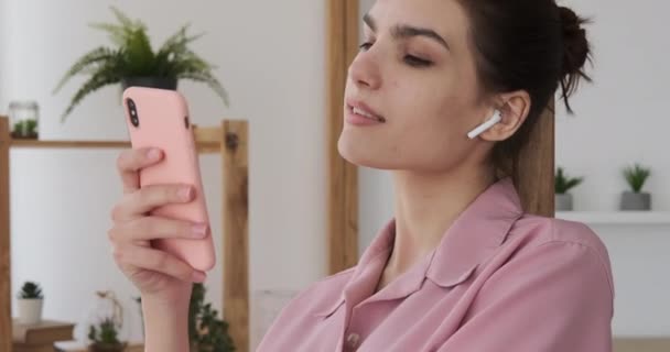 Vrouw die thuis muziek luistert met mobiele telefoon — Stockvideo