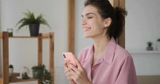 Ευτυχισμένη γυναίκα που χρησιμοποιεί το κινητό τηλέφωνο στο σπίτι — Αρχείο Βίντεο