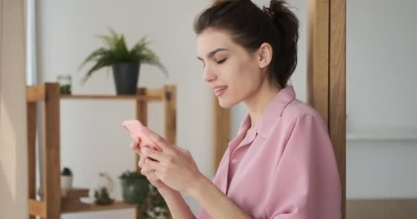 Mujer riendo usando el teléfono móvil en casa — Vídeos de Stock
