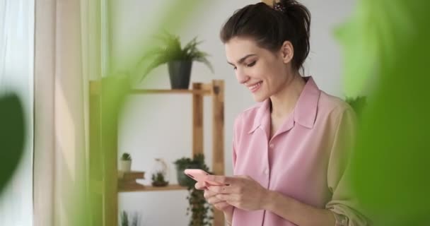 Mujer feliz usando el teléfono móvil en casa — Vídeos de Stock