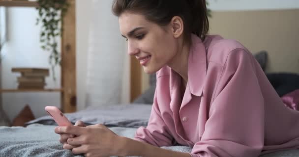 Mobilt használó nő otthon az ágyban — Stock videók