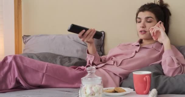 Mujer hablando por teléfono mientras ve la televisión en casa — Vídeo de stock