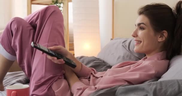 Žena se dívá na televizi a snídá v posteli — Stock video