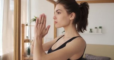 Spor kıyafetli kadın evde Aho mukha shvanasana çalışıyor.