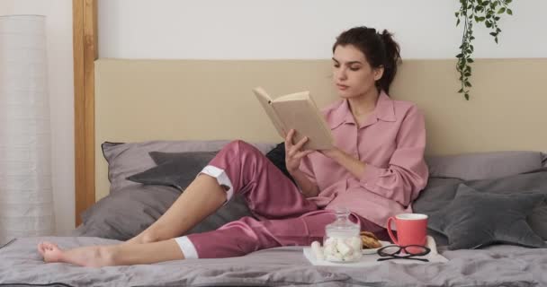 Mulher ler livro durante o café da manhã na cama — Vídeo de Stock