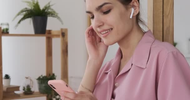 Γυναίκα ακούει μουσική χρησιμοποιώντας το κινητό τηλέφωνο στο σπίτι — Αρχείο Βίντεο