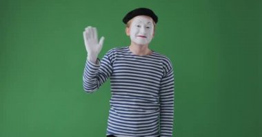 Pandomimci yeşil arka planda el sallıyor