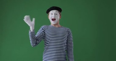 Pandomimci yeşil arka planda el sallıyor