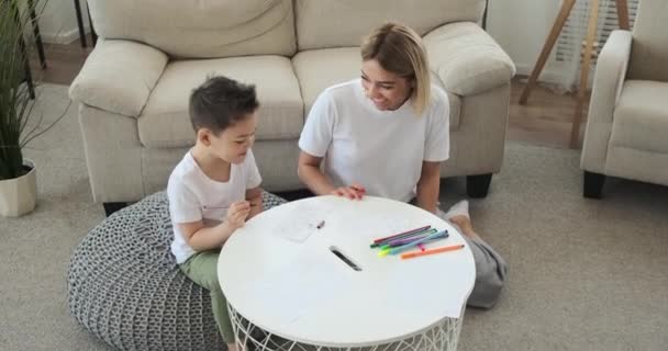 Joyful mother with son drawing on paper at home — Stock Video