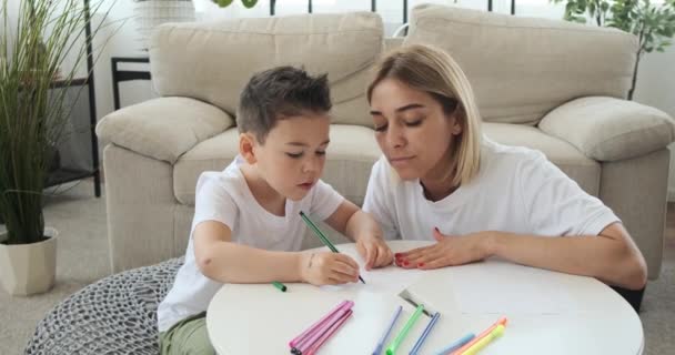 Мати з сином малює на папері вдома. — стокове відео