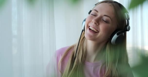 Femme écoute de la musique à l'aide d'écouteurs et danse à la maison — Video