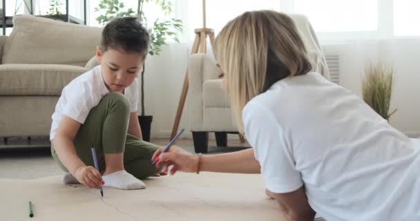 Mutter und Sohn zeichnen zu Hause auf Papierbogen — Stockvideo