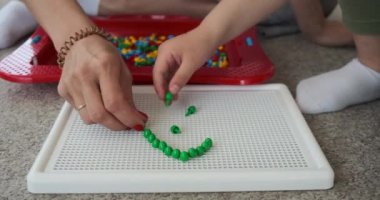 Anne ve oğul pim tahtasında şekil alıyorlar.