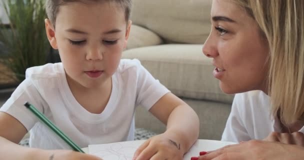 母亲和儿子在家里写书的时候分享秘密 — 图库视频影像