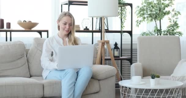Evdeki kanepede dizüstü bilgisayar kullanan mutlu kadın. — Stok video