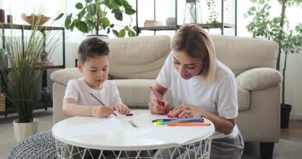 Мать с сыном рисуют на бумаге дома — стоковое видео