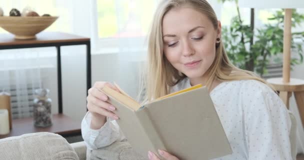 Vrouw die een boek leest in de woonkamer — Stockvideo