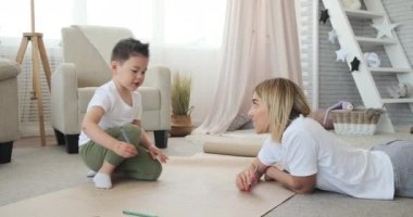 Anne ve oğul kağıt üzerine çizim yapıyorlar.