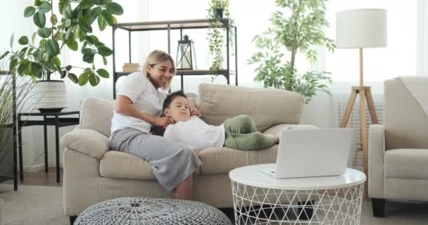 Moeder kietelen zoon tijdens het kijken naar film op laptop — Stockvideo