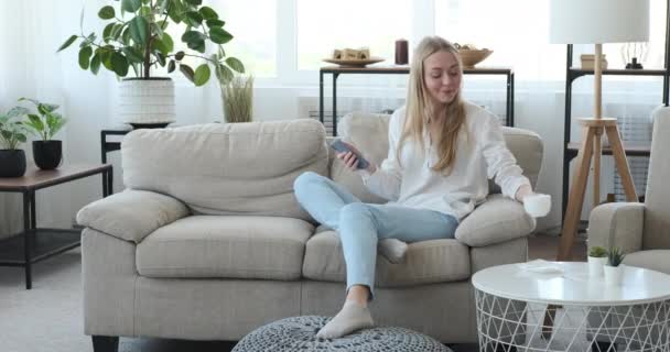 Femme utilisant téléphone portable et boire du café à la maison — Video