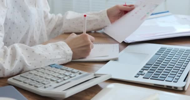 Empresaria usando calculadora y escribiendo notas en la oficina — Vídeo de stock