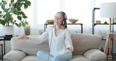Kanepede kulaklıkla müzik dinlemekten hoşlanan neşeli bir kadın.