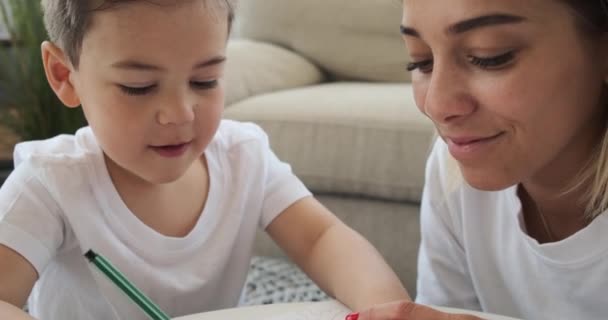 Madre con hijo dibujo sobre papel en casa — Vídeos de Stock