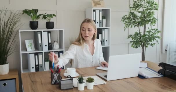 Empresaria que usa laptop y escribe notas en su diario en la oficina — Vídeos de Stock
