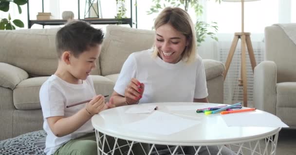 Fröhliche Mutter mit Sohn zeichnet zu Hause auf Papier — Stockvideo