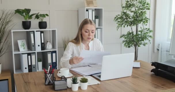 Mujer de negocios analizando documentos y notas de escritura en el escritorio — Vídeos de Stock