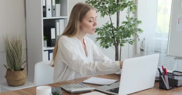 Femme d'affaires utilisant une calculatrice et écrivant des notes au bureau — Video