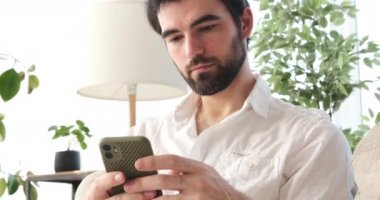 Evde cep telefonu kullanan adam.