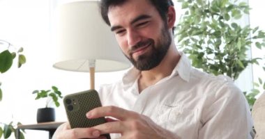 Evde cep telefonu kullanan adam.