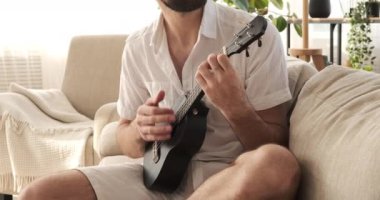 Adam evde şarkı söylüyor ve gitar çalıyor.