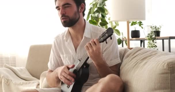 Hombre cantando canción y tocando la guitarra en casa — Vídeos de Stock